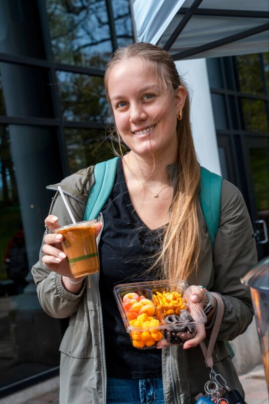 Student with iced coffee and snack box. 