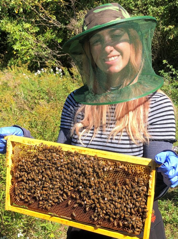 Students holds a hive frame of honey bees