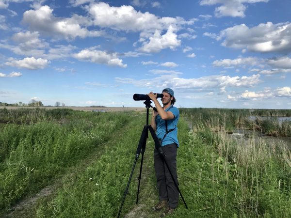 Will Keller from the class of 2023 uses a camera to take pictures in a field