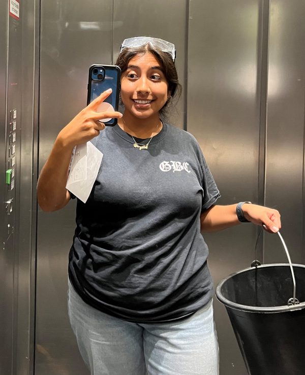 Crystal Mendoza holding a bucket and a cell phone in an elevator