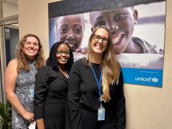 Three K Alumnae at in front of a UNICEF poster in Kenya