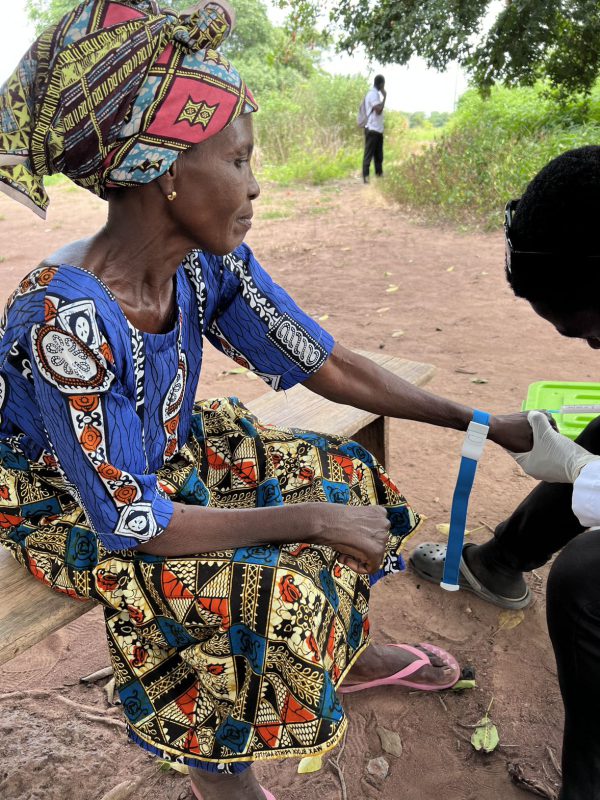 Ghanian woman wearing colorful clothes provides a blood sample