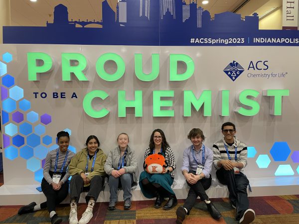 Five students and a professor posing with Bippy under a sign that says Proud Chemist