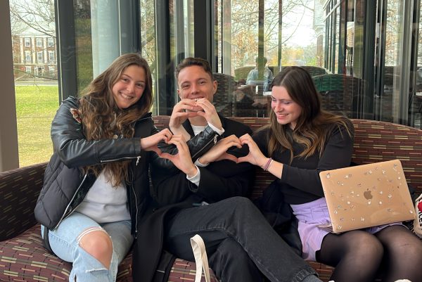 International students make hearts with hand gestures at Hicks Student Center