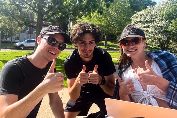 Three students giving thumbs up on campus