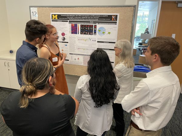 Vivian Schmidt presenting her neuroscience research poster to five people at the University of Michigan