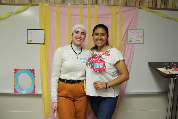 Two students at a photo booth with one holding a BFFs sign