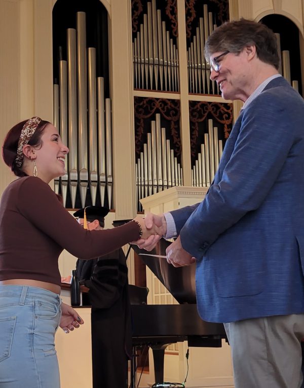 A students shakes hands with faculty while receiving an award on Honors Day 2023