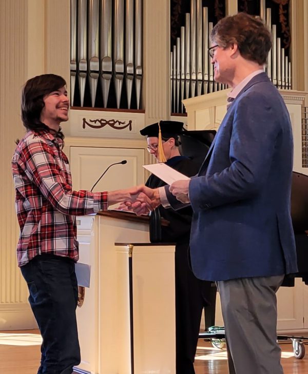 A student receives an award while shaking hands with a faculty member on Honors Day 2023