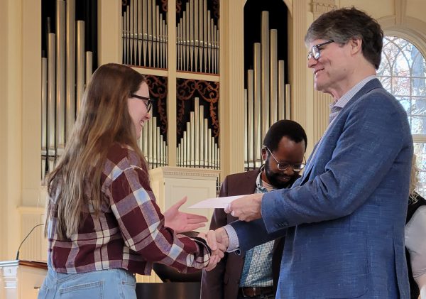 A student receives an award while shaking hands with a faculty member on Honors Day 2023