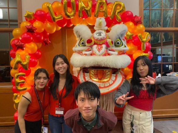 Emmeline Wendel with friends and a dragon costume next to a banner that says Happy Lunar New Year