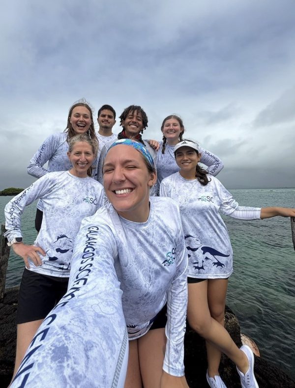 Marine research team poses near the ocean after a day of collecting data