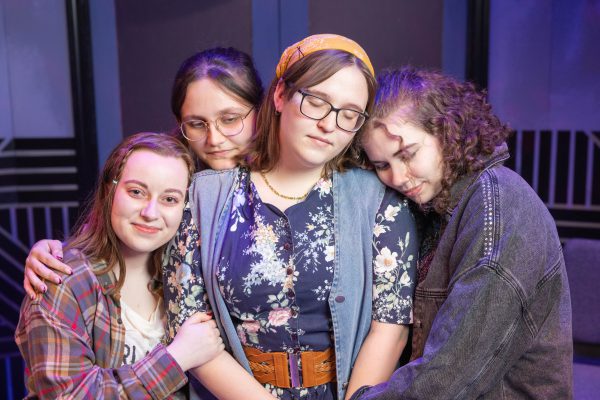 Four actors from "The Most Massive Woman Wins" huddle during a rehearsal