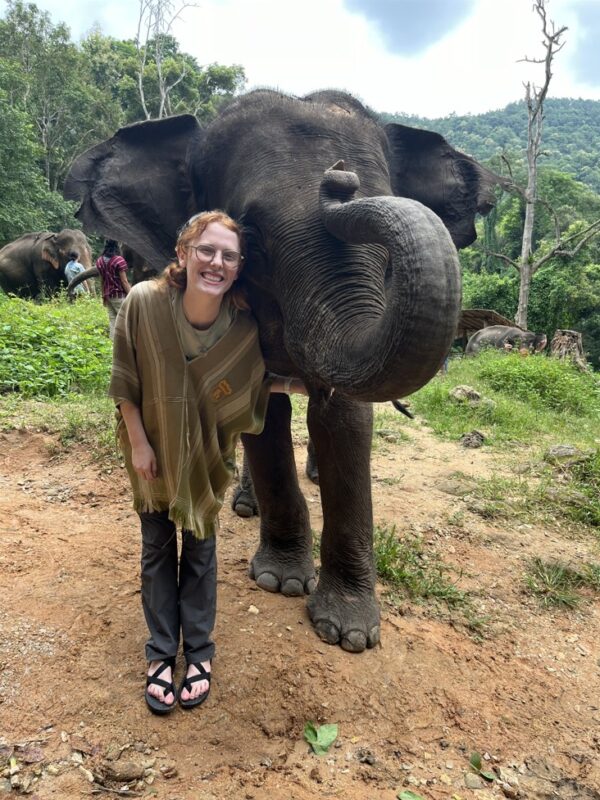 Nat Ward on study abroad standing with an elephant