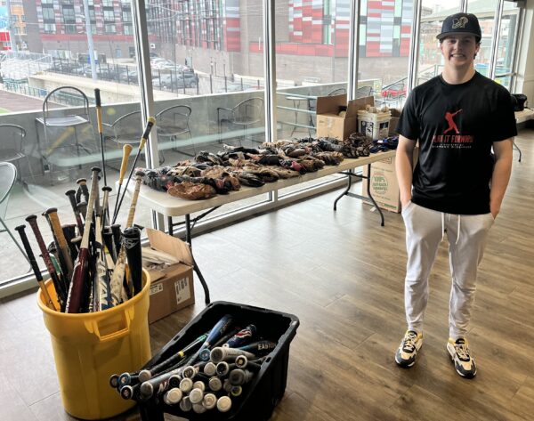 Nolan Jominy with tables, tubs and buckets full of donated baseball equipment