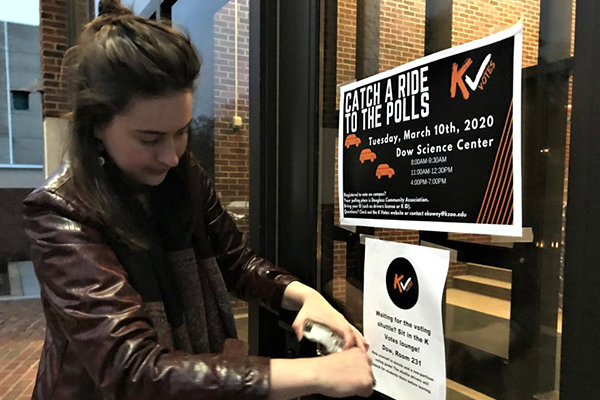 student hanging a poster encouraging people to vote