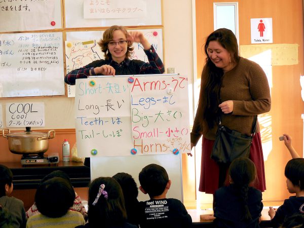 Two K students with a poster with English words and their Japanese equivalents