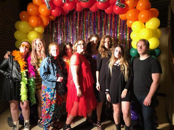 Students posing in front of a rainbow balloon arch