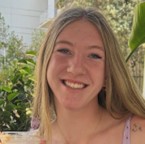 Jordan Wesaw, a smiling woman with long blonde hair parted in the middle, posed against a bright background with greenery.