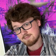 Jack Dewey, a person with wavy brown hair, glasses, and a light beard, wearing a gray striped button-down shirt over a red top against a vibrant pink and purple artwork background.