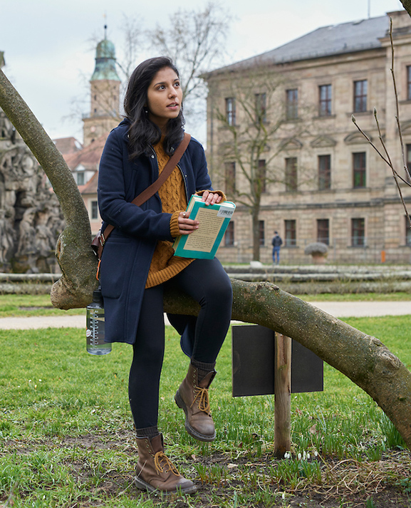 student holding book in a park in Erlangen Germany