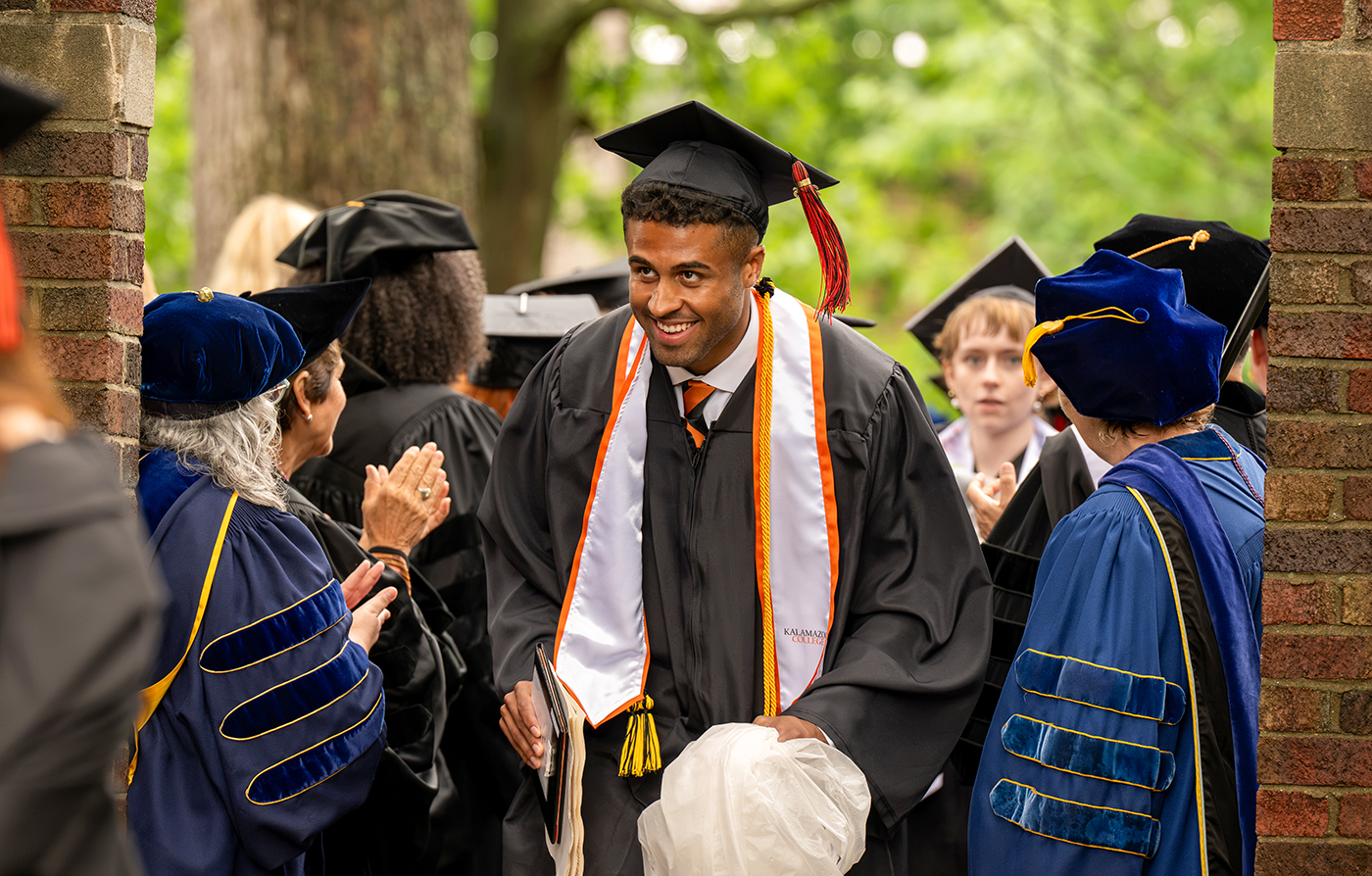 Graduate walking through faculty members wearing caps and gowns. 