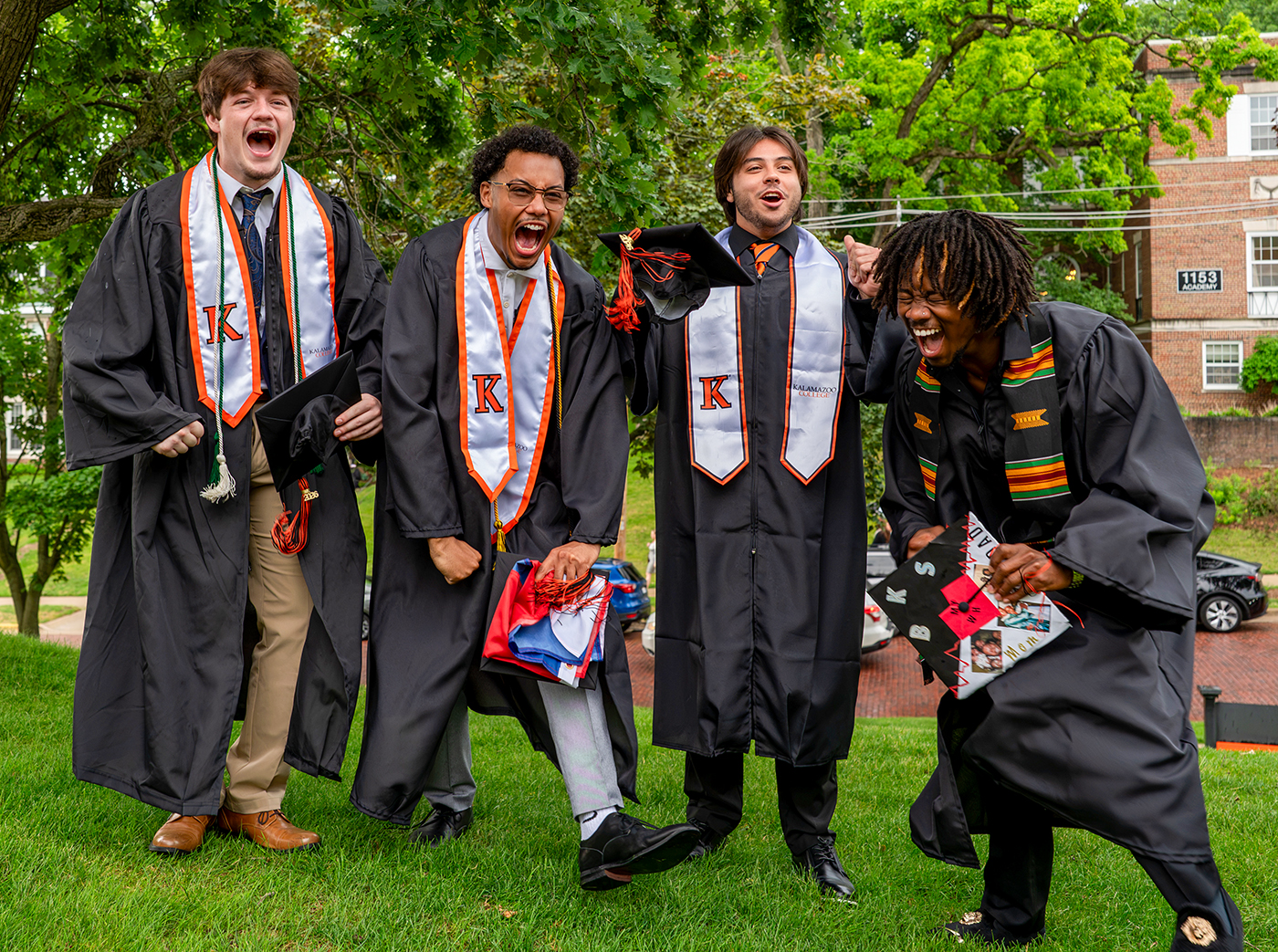Four graduates celebrating outside the Light Fine Arts building.