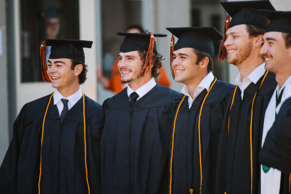 Five graduates posing for a photo at Commencement.