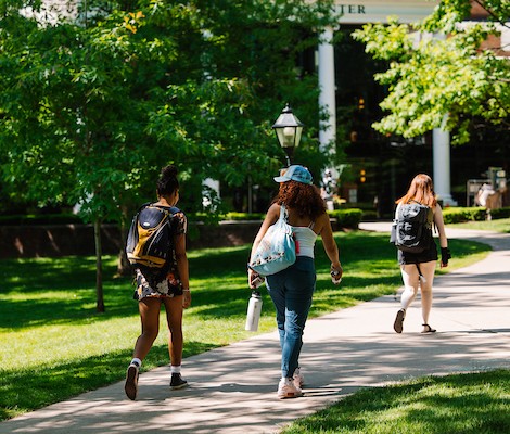 Three students with backpacks on walking. 