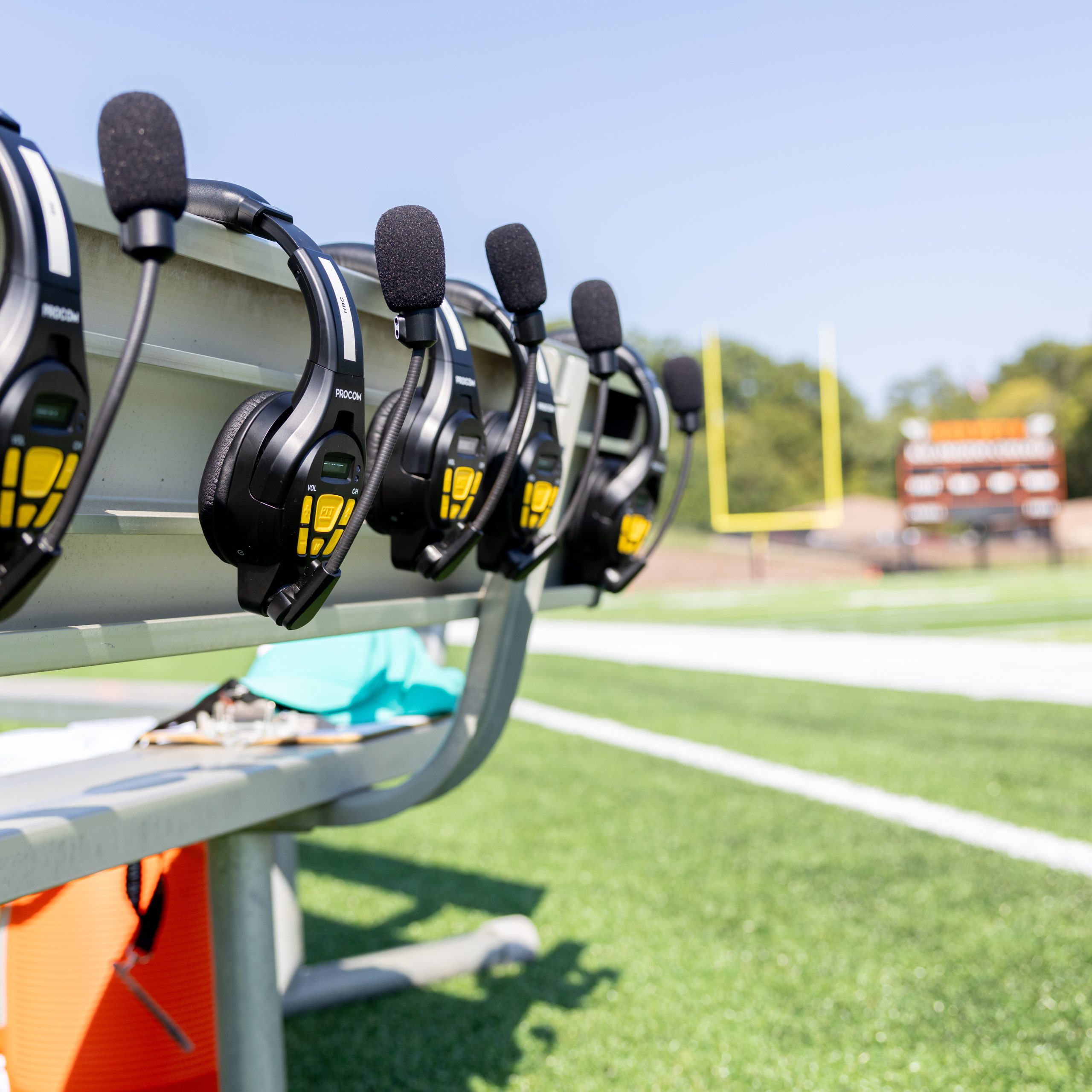 Headsets for football hanging from a bench on the field before a game.