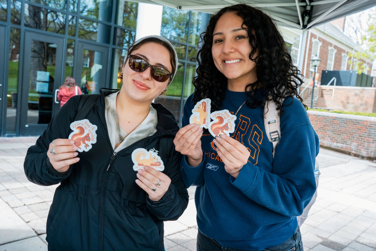 Two students holding squirrel stickers. 