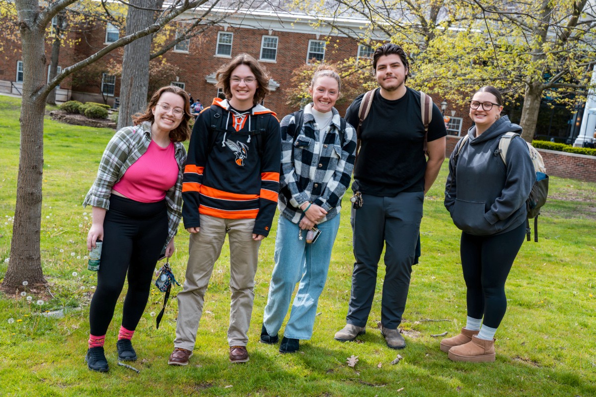 Five students standing together on the quad. 