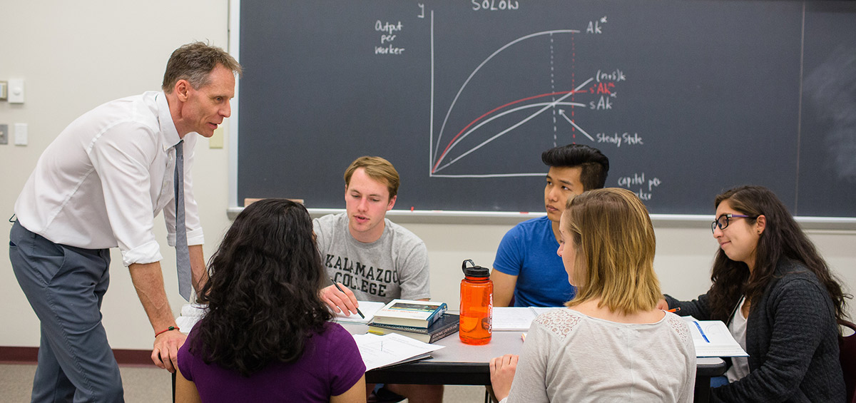 A professor speaking with a small group of students in class