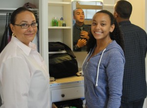 Ronnie Russell puts on a tie while mom, Paulette, and younger sister, Kathleen, help arrange his Harmon Hall room