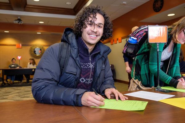 Male student smiles and signs Declaration of Major Day forms