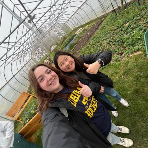Two students give a thumbs up at the Hoop House