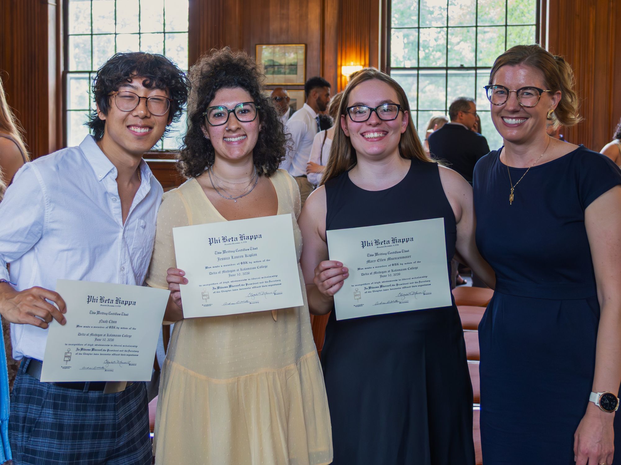Three students smiling with a faculty member at the Phi Beta Kappa induction ceremony