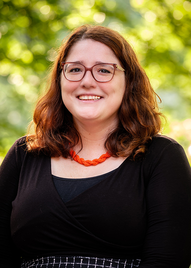 Headshot of Amanda Bidinger Assistant Director of Development. A blurred natural setting is visible behind her.