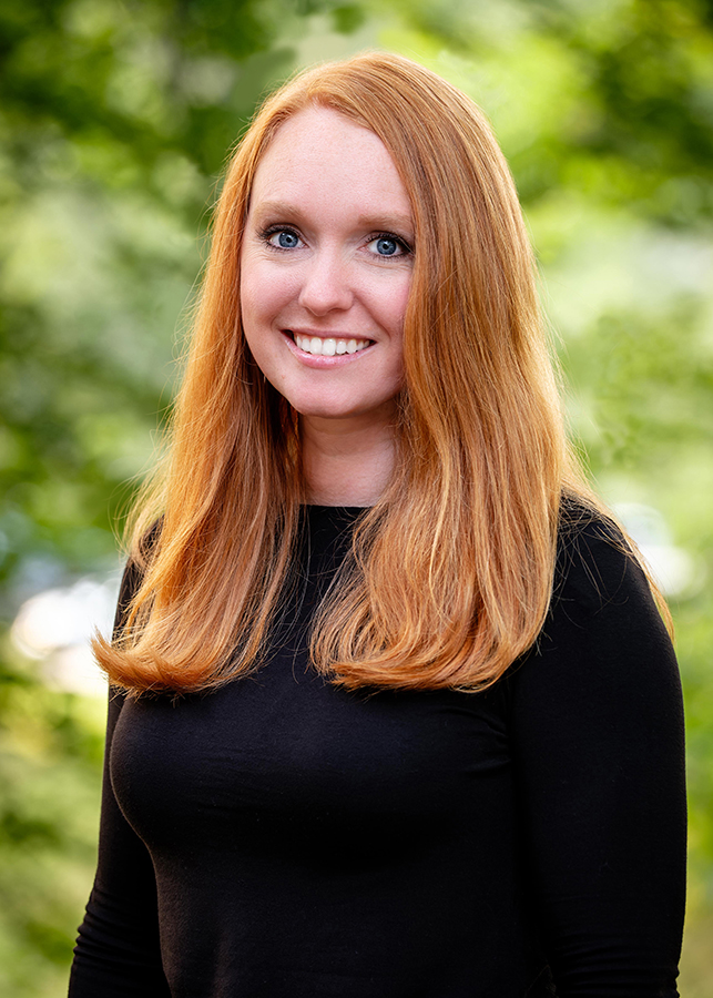Headshot of Sarah Kerry Assistant Director of Development. A blurred natural setting is visible behind her.