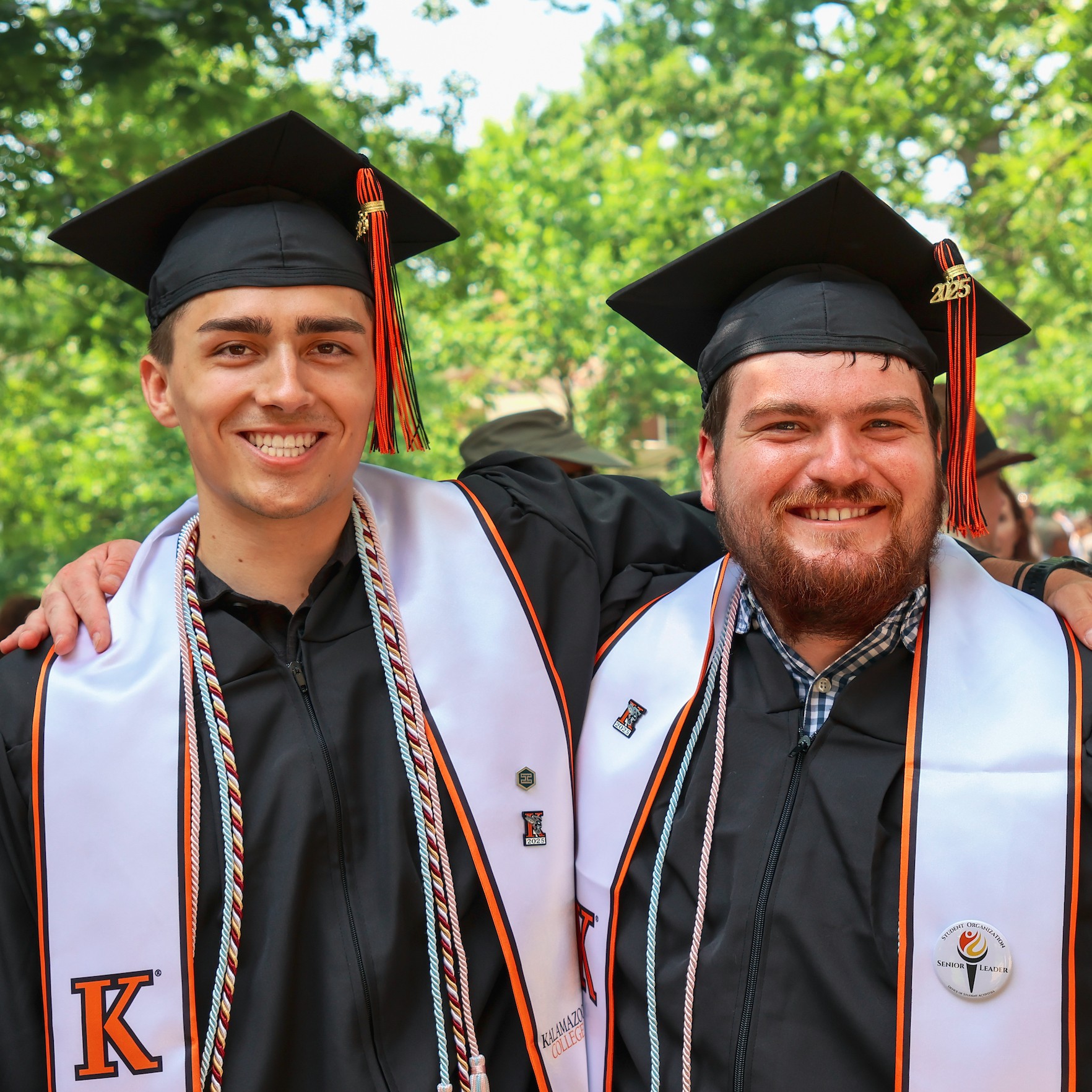 Two students with their arms around each other at Commencement in 2025