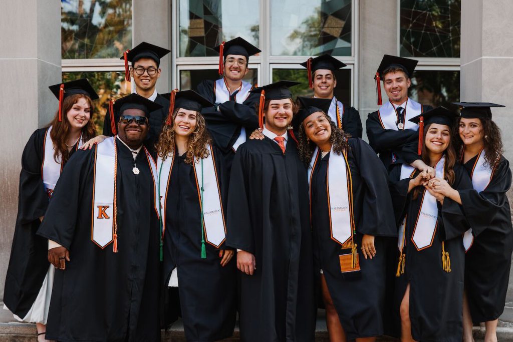 Eleven graduates in robes on the steps of LFA