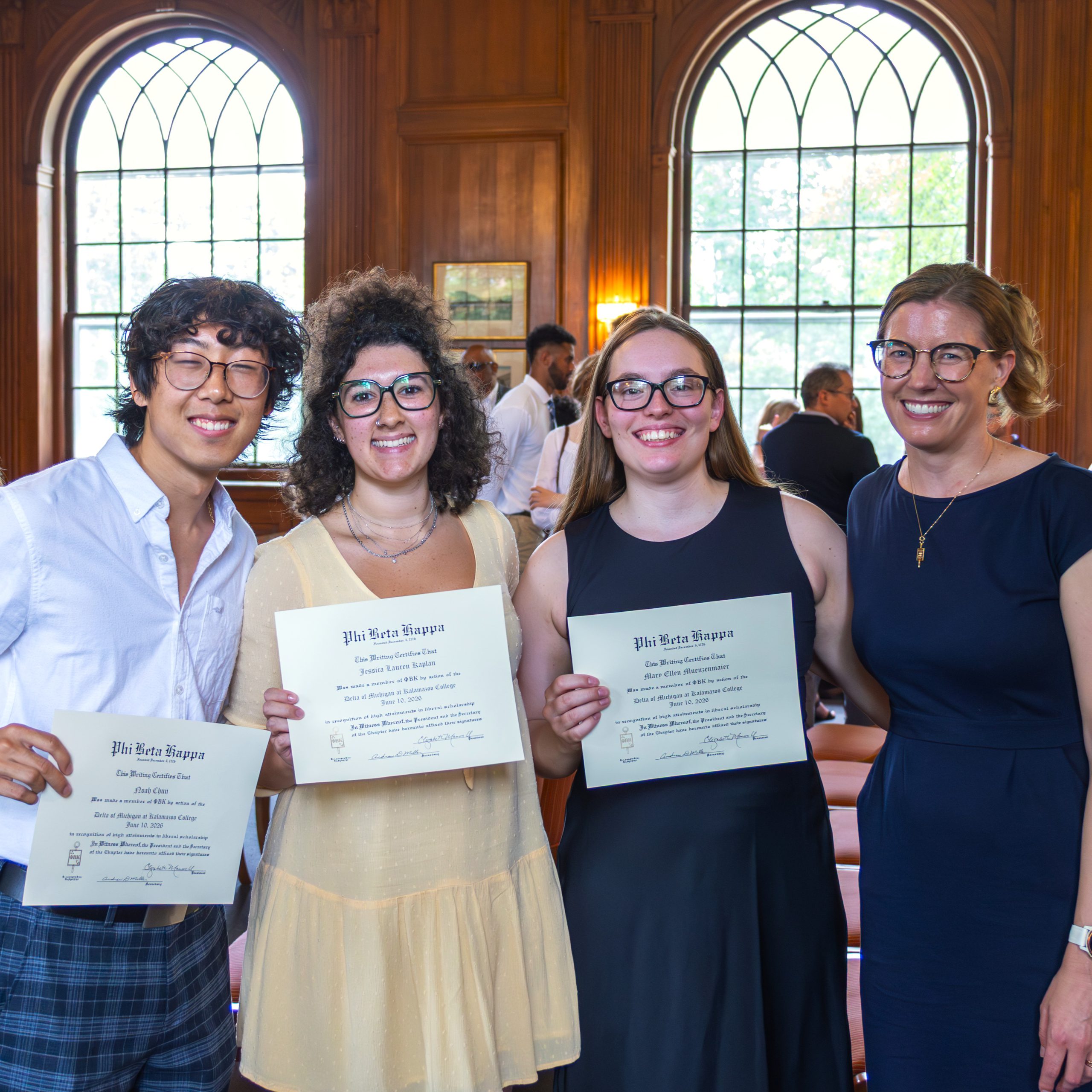 Three students smiling with a faculty member at the Phi Beta Kappa induction ceremony