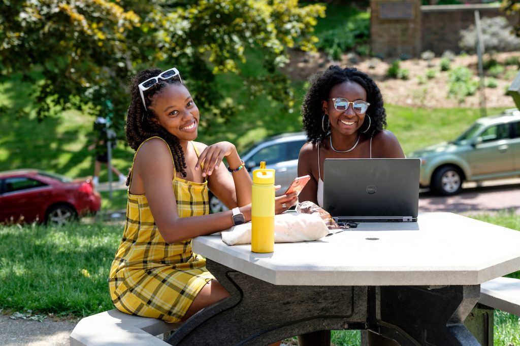 two girls sitting outside at a table studying