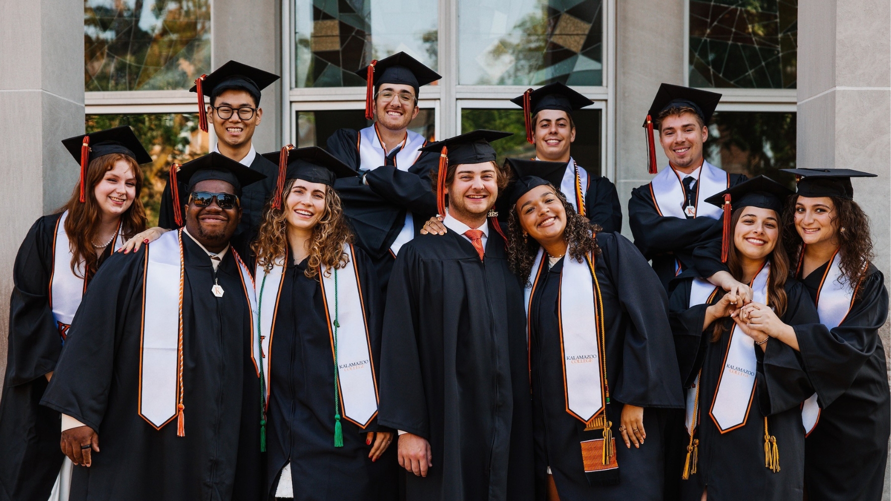 Group of 11 graduates in robes smiling