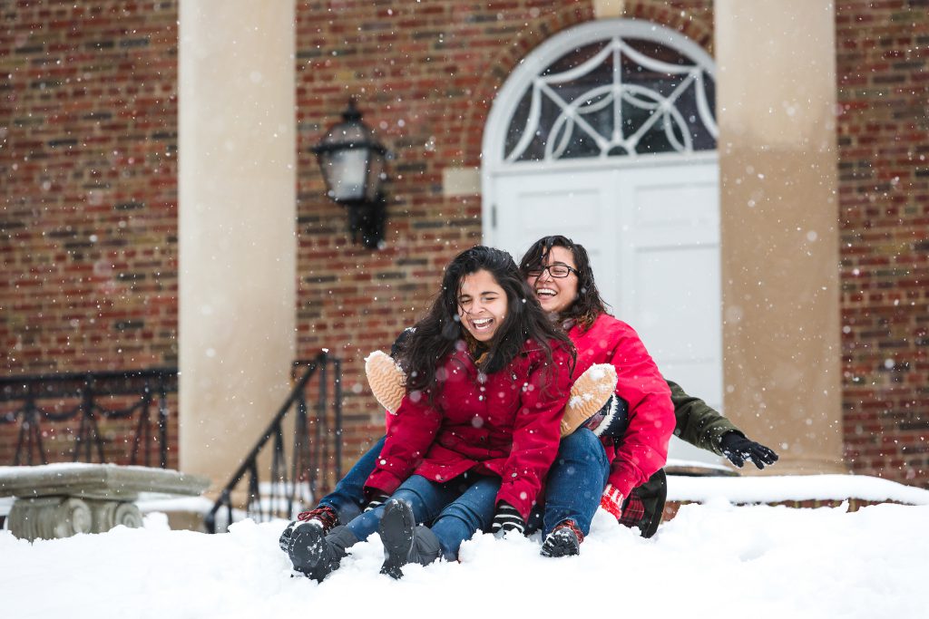 Girls in red coats sledding on the quad